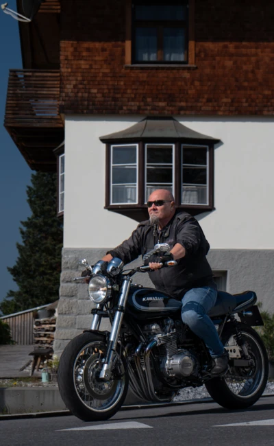 Mann f&auml;hrt auf Kawasaki-Motorrad neben einem Wohnhaus