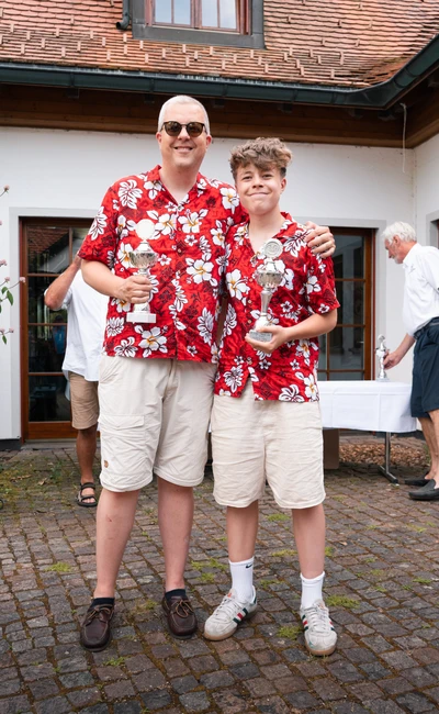 Zwei Personen in bunten Hemden halten Pokale nach der Lindau-Klassik Rallye