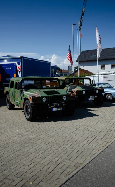 Zwei gr&uuml;ne Milit&auml;rfahrzeuge vor einem blauen Transporter auf dem American-Dream-V8 Treffen in Lindenberg