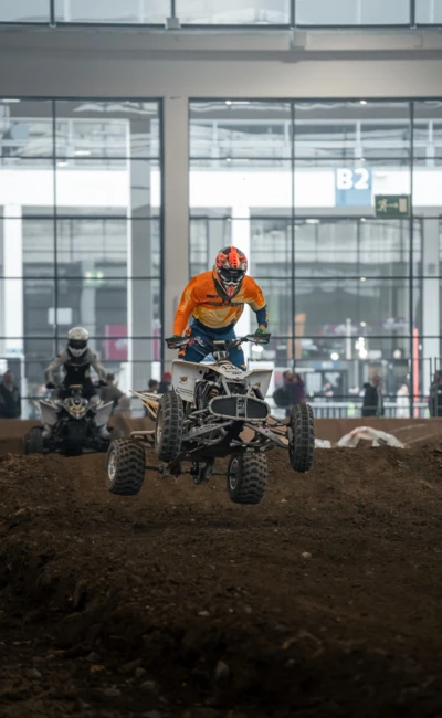 Motorradwelt 2026: Quadfahrer springt &uuml;ber einen Erdh&uuml;gel in einer Halle