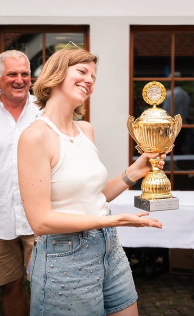 Frau pr&auml;sentiert Pokal auf der Lindau-Klassik Rallye, im Hintergrund Mann