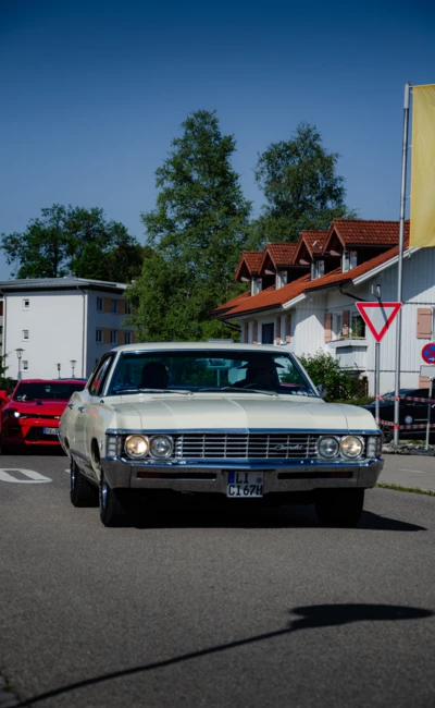 Wei&szlig;er Oldtimer f&auml;hrt durch eine Stra&szlig;e beim American-Dream-V8 Treffen in Lindenberg