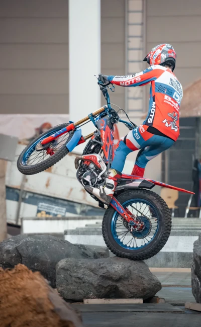 Motorradfahrer in roter und blauer Kleidung Balanciert auf Felsen bei der Motorradwelt 2026