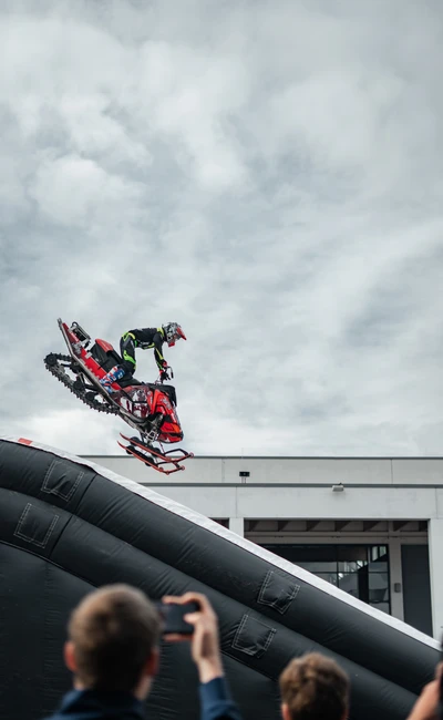 Sportler springt auf Schnee-Motorrad von einer Rampe bei Tuning World Bodensee 2026