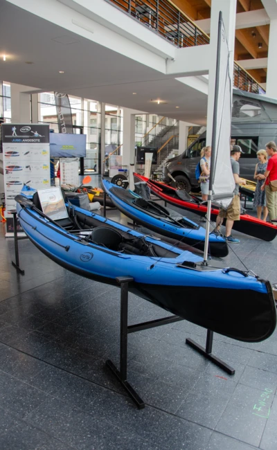 Blaue Kajaks auf einer Messe mit St&auml;nden und Besuchern in Friedrichshafen