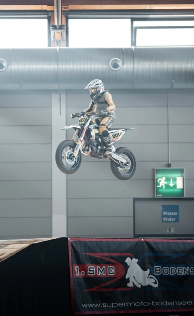 Motorradfahrer springt mit einem Supermoto-Motorrad &uuml;ber eine Rampe auf der Motorradwelt 2026 Messe