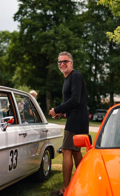Mann steht neben silbernem Auto bei der Lindau-Klassik Rallye