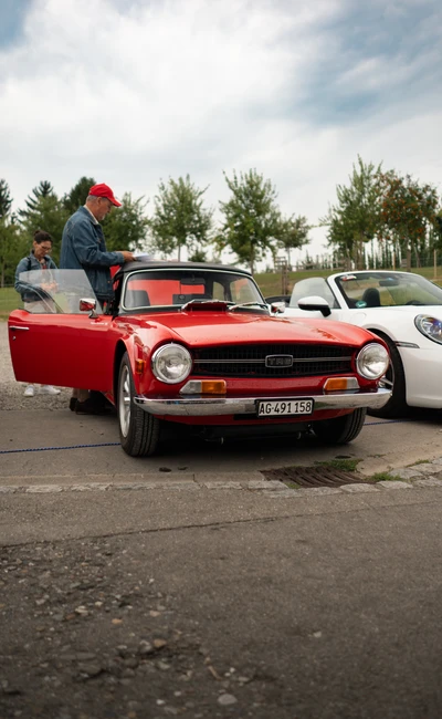 Roter Oldtimer steht neben wei&szlig;em Sportwagen auf der 10. Spa&szlig;rallye Bodensee 2026