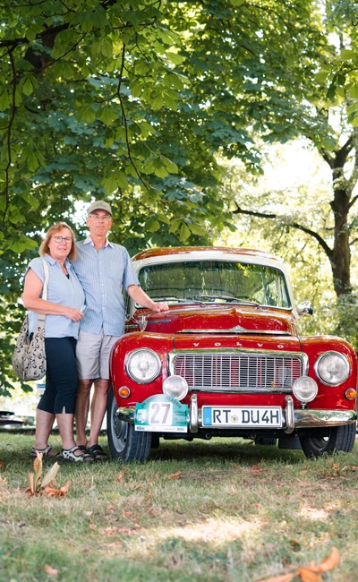 Paar posiert vor einem roten Oldtimer w&auml;hrend der Lindau Klassik Rallye