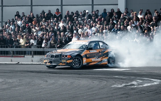 BMW-Fahrzeug mit orangefarbenem Design driftet auf der Tuning World Bodensee 2026.