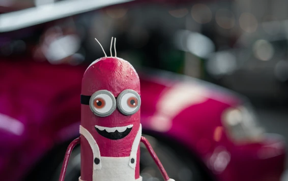 Bunte Figur mit gro&szlig;en Augen steht vor einem modifizierten Fahrzeug auf der Tuning World Bodensee 2026.
