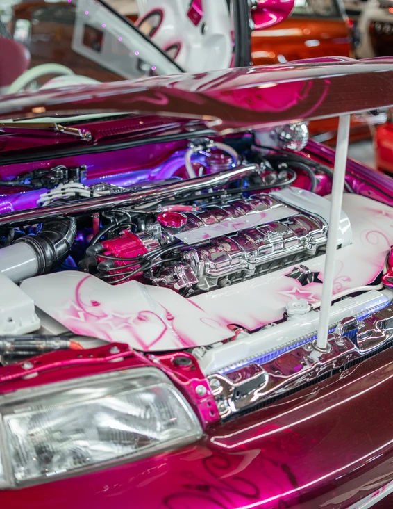 Tuning World Bodensee 2026 in Friedrichshafen Geöffneter Motorraum eines getunten Autos mit pinkem Lack und verzierten Teilen auf der Tuning World Bodensee 2026
