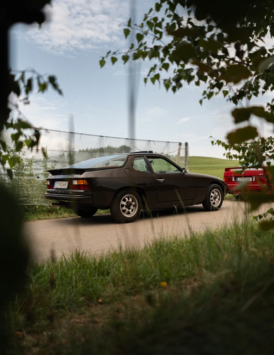 10. Spaßrallye Bodensee 2026 Zwei Fahrzeuge, ein schwarzer Porsche 924 und ein rotes Auto, auf einer Straße